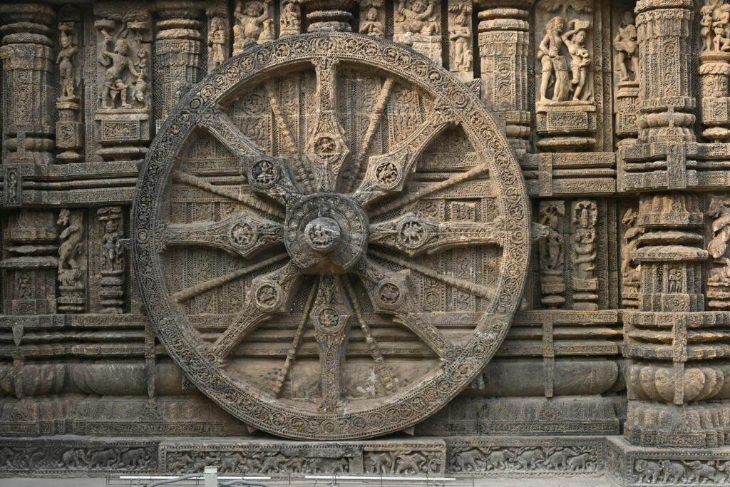 Detailed stone carving of a wheel on Konark Sun Temple, showcasing ancient Hindu architecture.